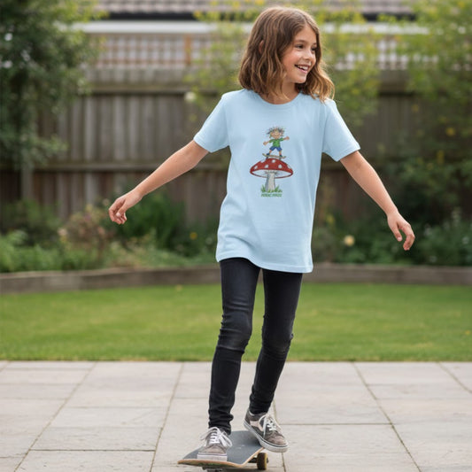 Child wearing a light blue t-shirt with a crayon mushroom skate design, standing on a skateboard outdoors.