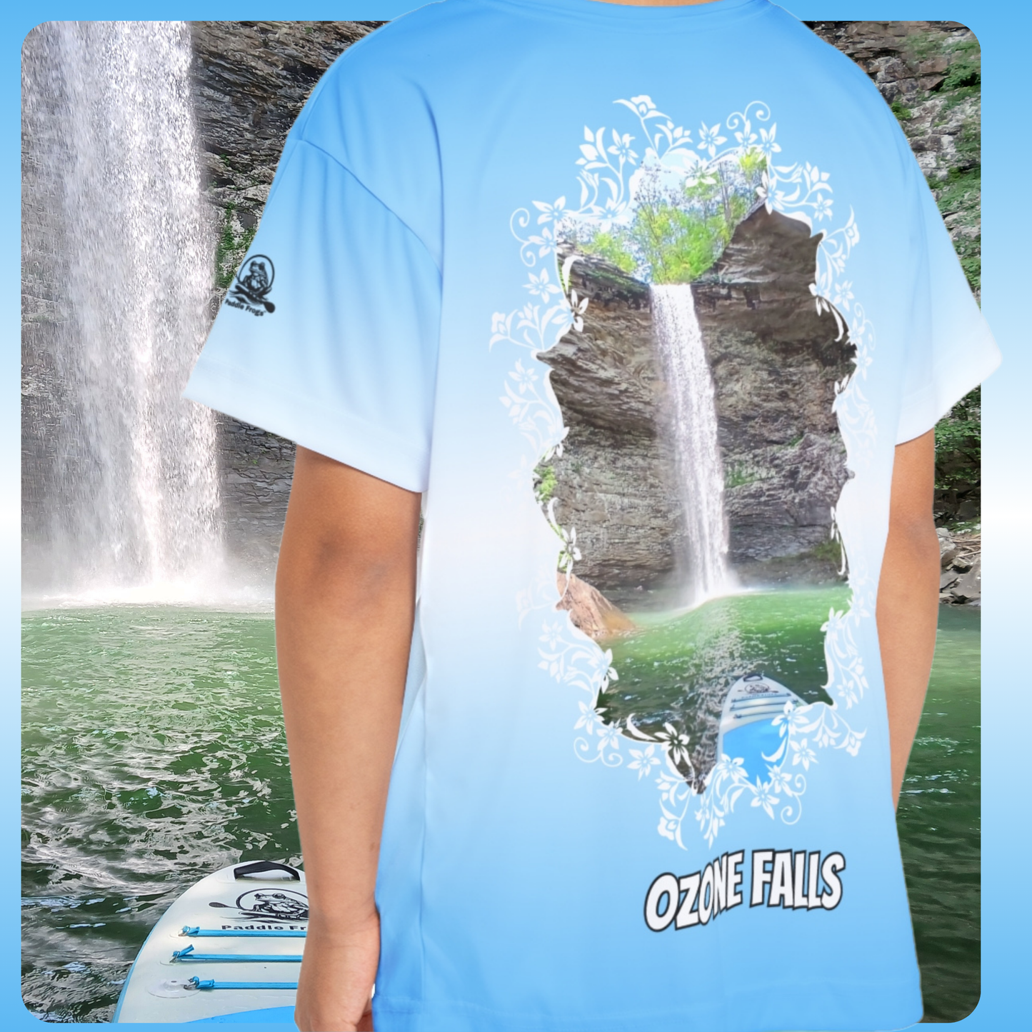 Paddle Frogs Kids Jersey | Person wearing a blue t-shirt with a waterfall design and 'Ozone Falls' text, standing in front of a waterfall.