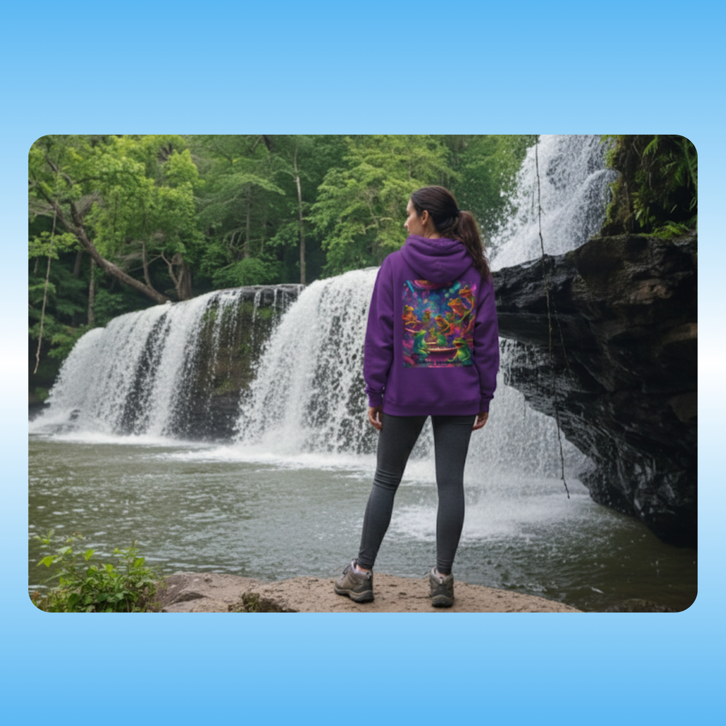 Galactic Mindbender Hoodie Person wearing a purple hoodie with a colorful design, standing in front of a waterfall.