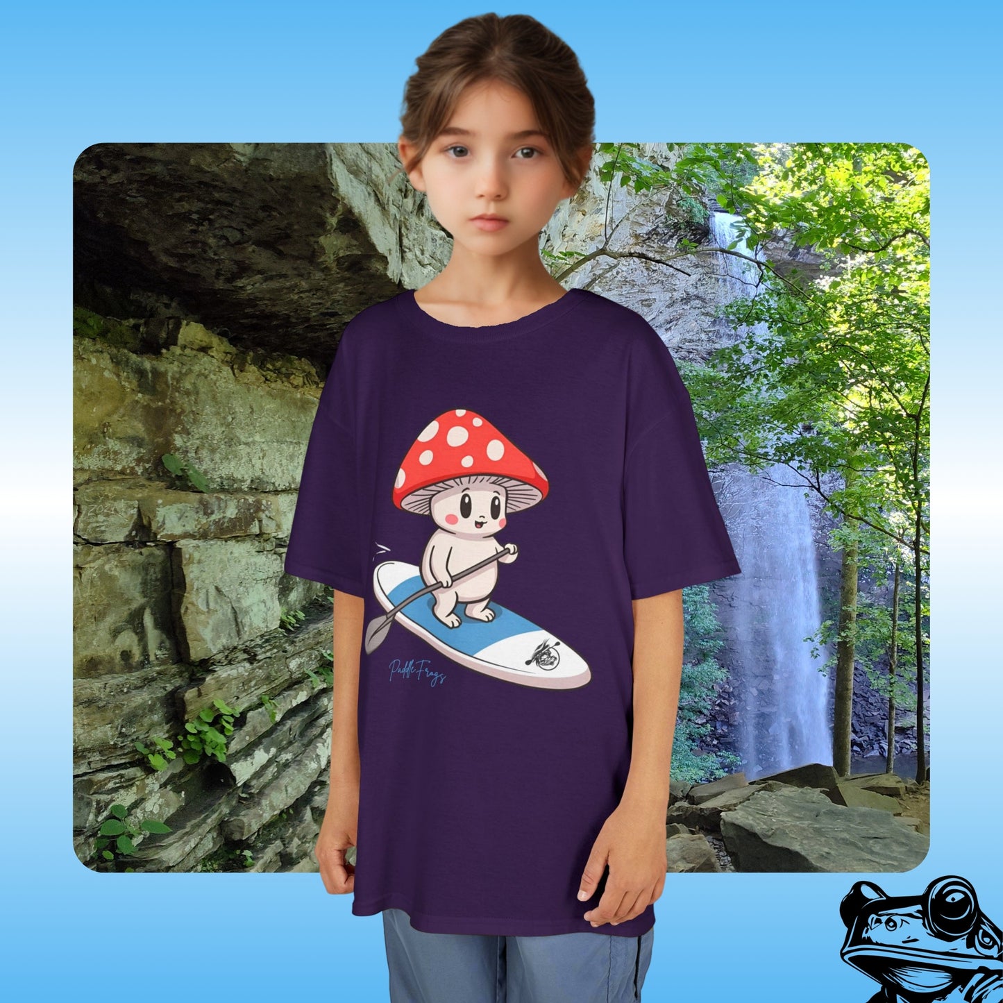 Kids purple T-Shirt with mushroom creature riding the Divine Escape paddle board by Paddle Frogs Ozone Falls in the background | Child wearing a purple t-shirt with a cartoon character design, standing in front of a natural landscape with a waterfall.