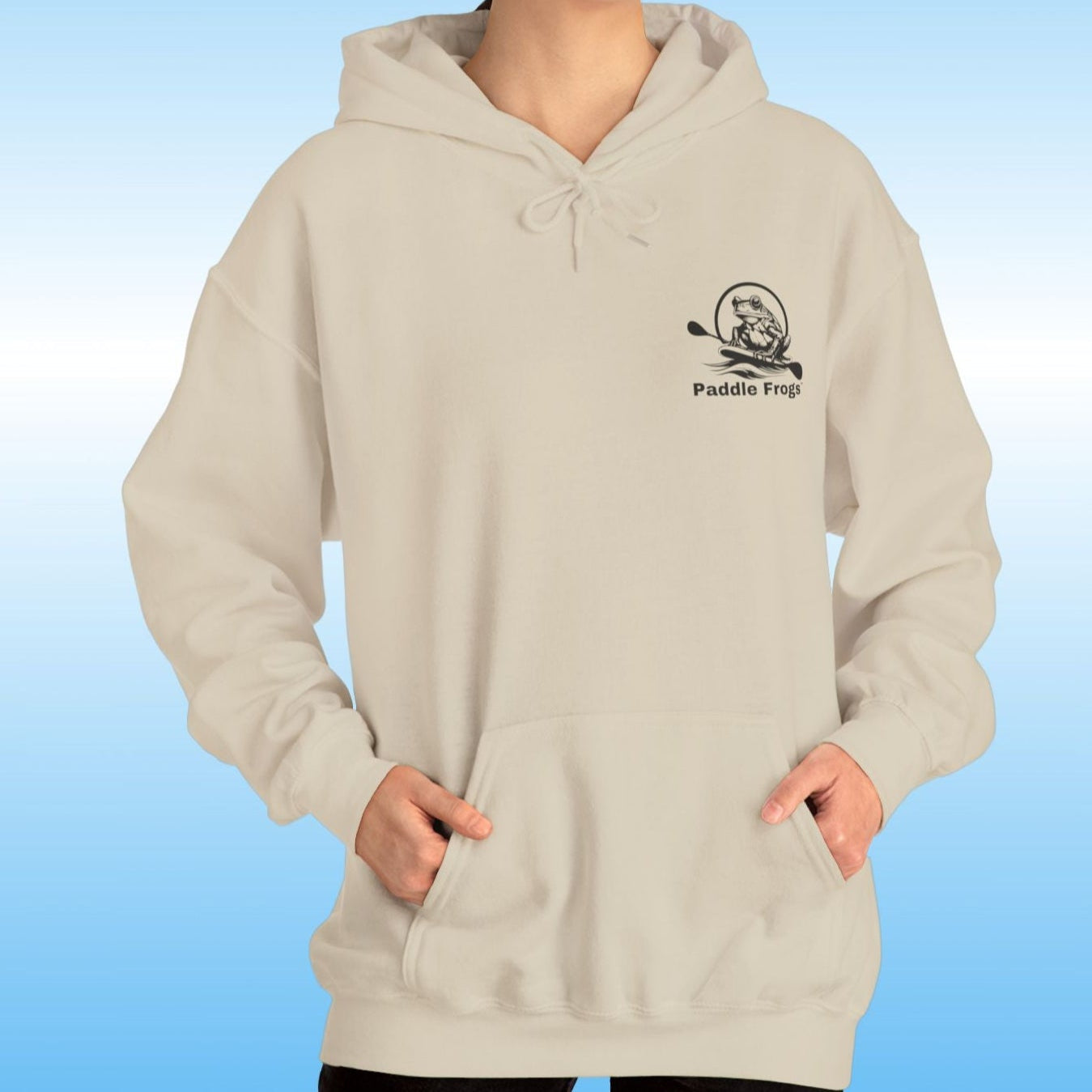 Paddle Frogs original Hoodie in multiple colors Paddle boarding frog Person wearing a sand beige hoodie with a logo on a blue background