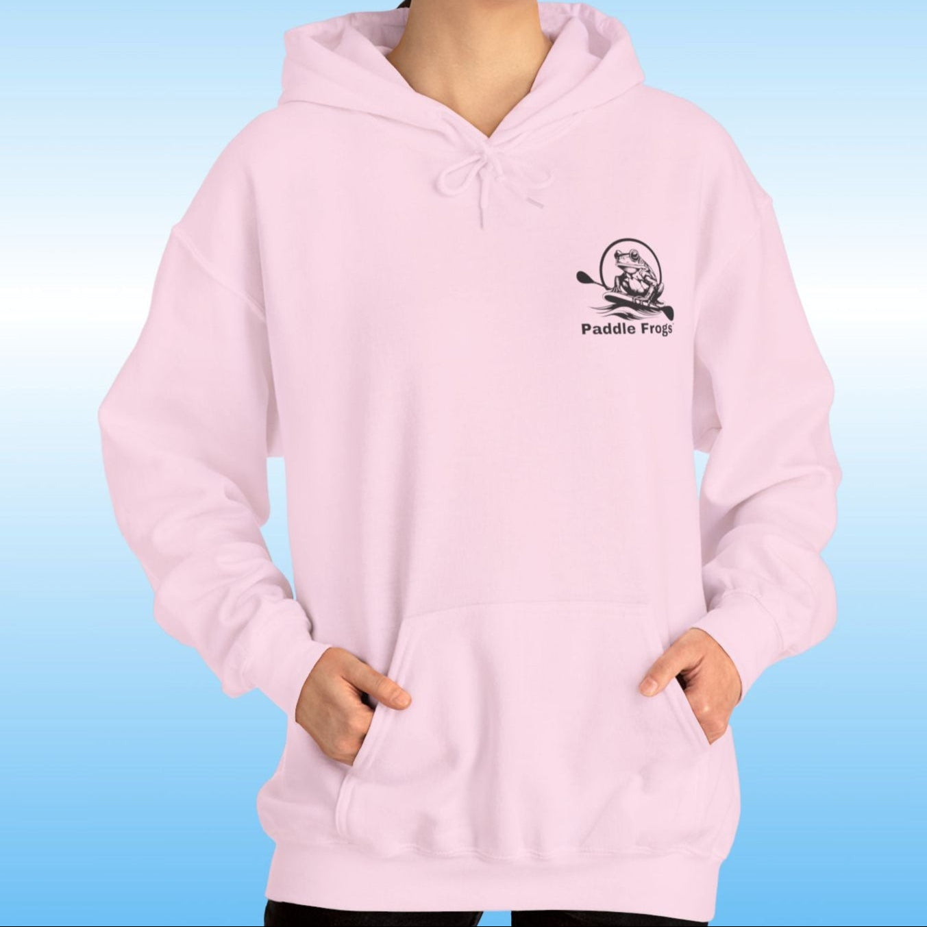 Paddle Frogs original Hoodie in multiple colors Person wearing a light pink hoodie with a paddle boarding frog logo on a blue background