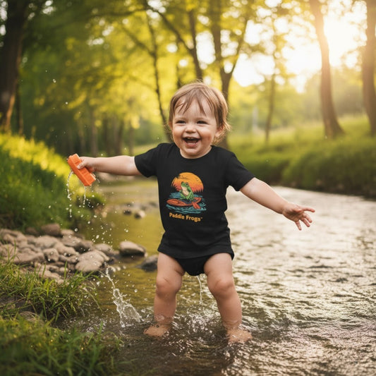Playing in the creek wearing the black Sunset Frog Paddle Board Explorer Toddler Tee "Skate & Paddle Frogs™