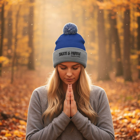Woman wearing a blue and gray beanie with 'Skate & Paddle' logo in an autumn forest. The Summit & Surf Beanie: A Paddle Frogs Anthem by Paddle Frogs™ Outdoor Gear Skate & Paddle headwear