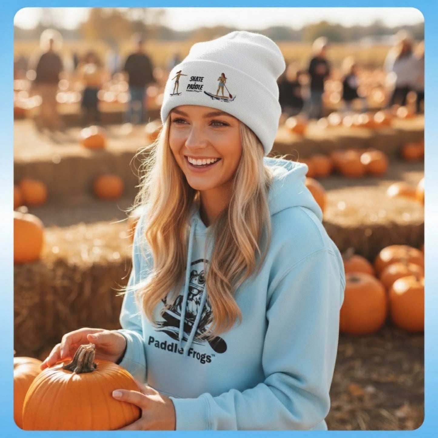 Tides & Trails Beanie: Life in Balance, Skate & Paddle Woman holding a pumpkin at a pumpkin patch wearing a light blue hoodie and white beanie.