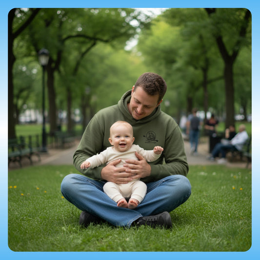 olive Chaos Green Paddle Frogs Outdoor Gear Hoodie pull over coat Man holding a baby in a park with green trees and grass.