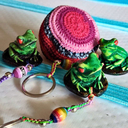 Colorful keychain with frogs and a pink and black round foot bag on a white background