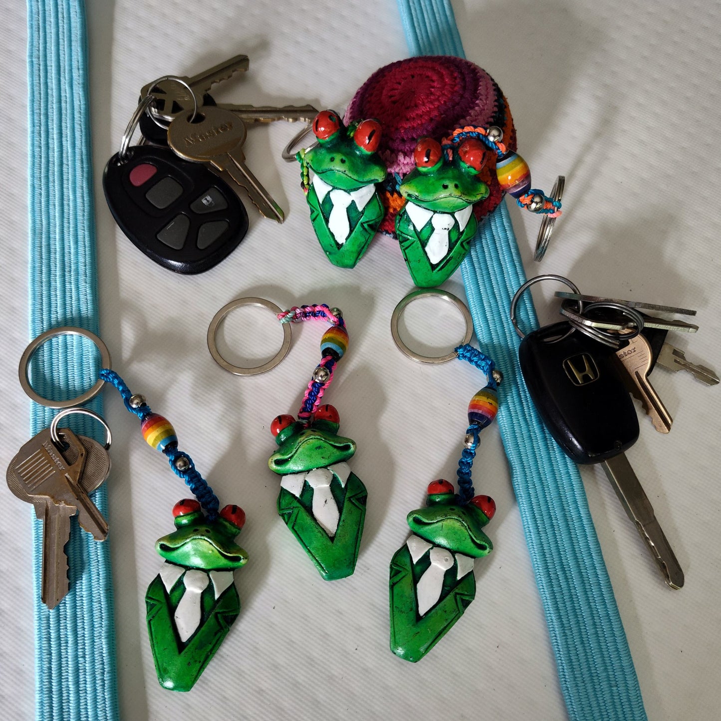 Colorful keychains with green frog designs on a white surface