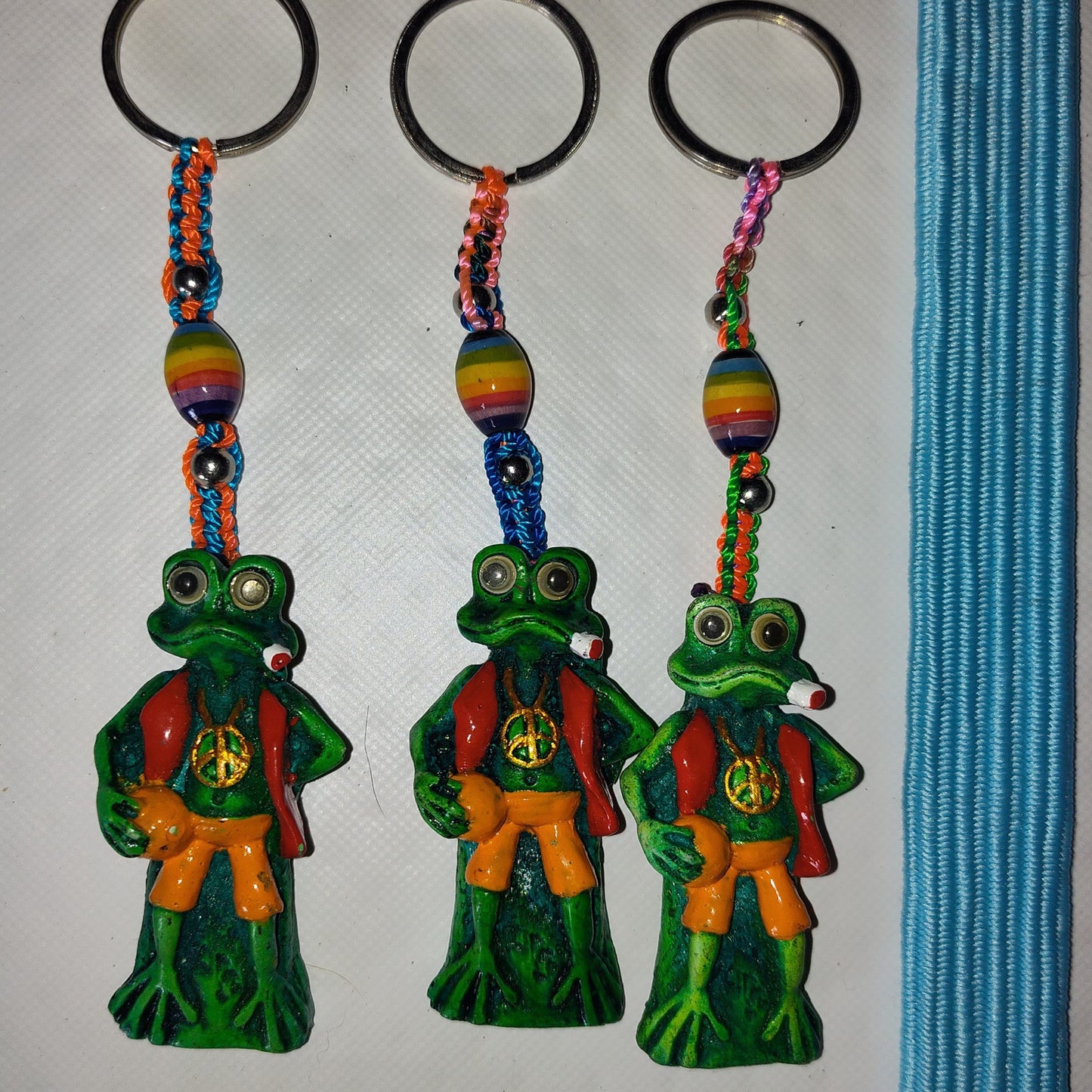 Three frog-shaped keychains with colorful beads on a white background