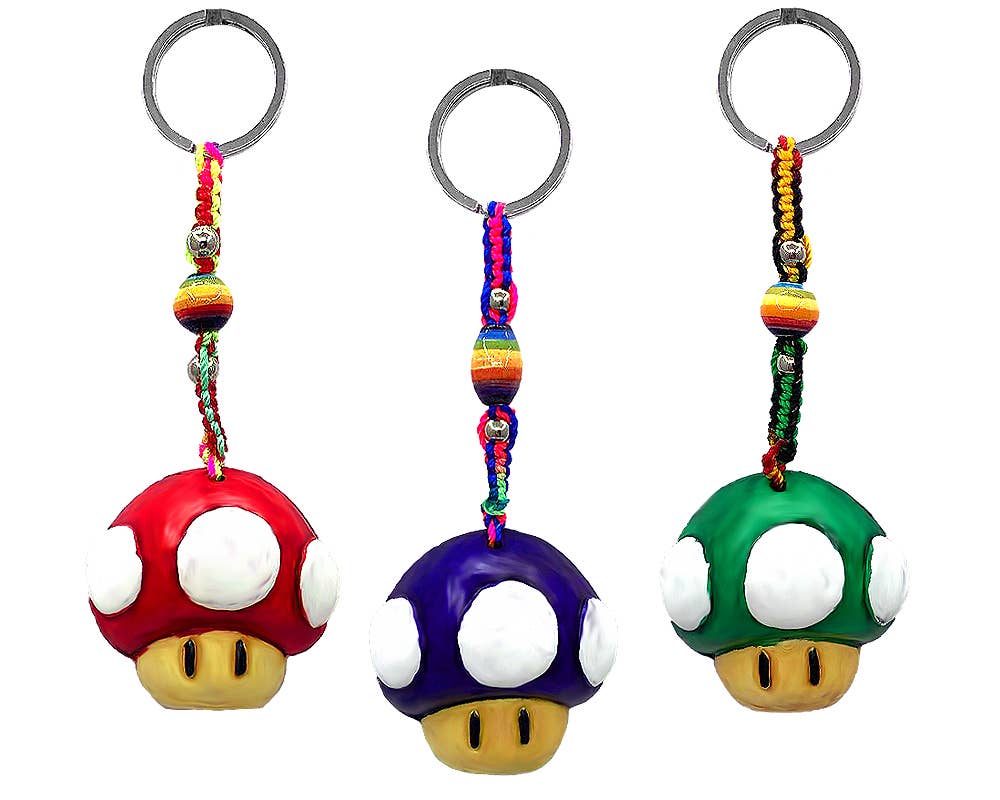 Three Super Mushroom-themed keychains on a plain white background, featuring red, blue, and green mushroom charms with white caps, yellow feet, and braided rainbow cords attached to silver keyrings.