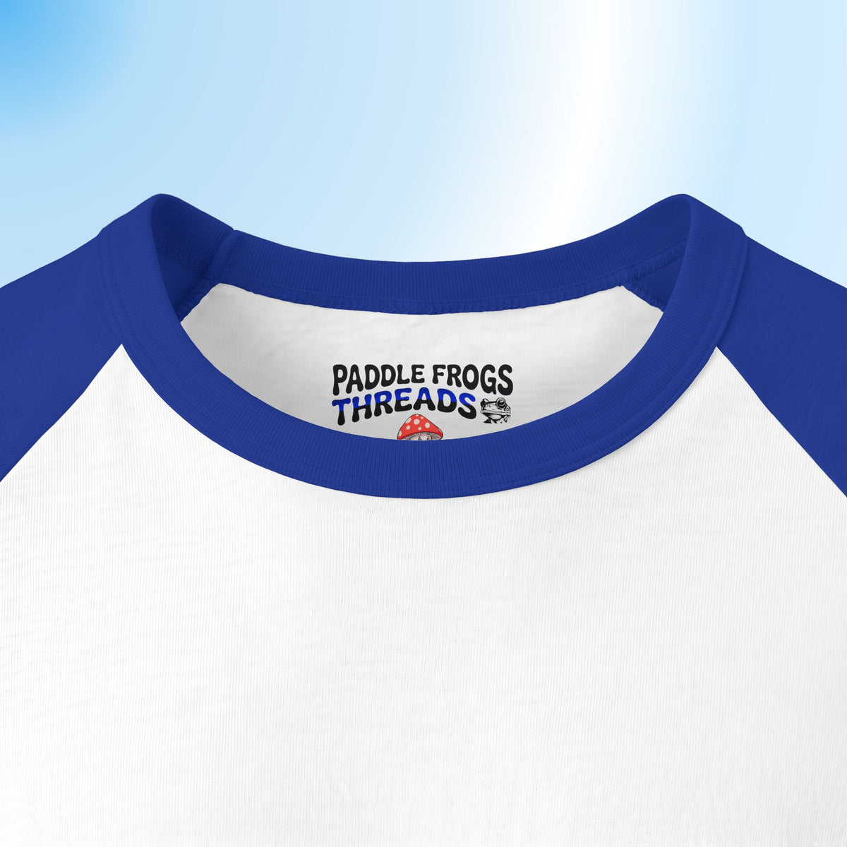 Close-up of a raglan-style shirt neck with a white body, blue collar and sleeves, and a visible 'PADDLE FROGS THREADS' logo printed inside the collar.