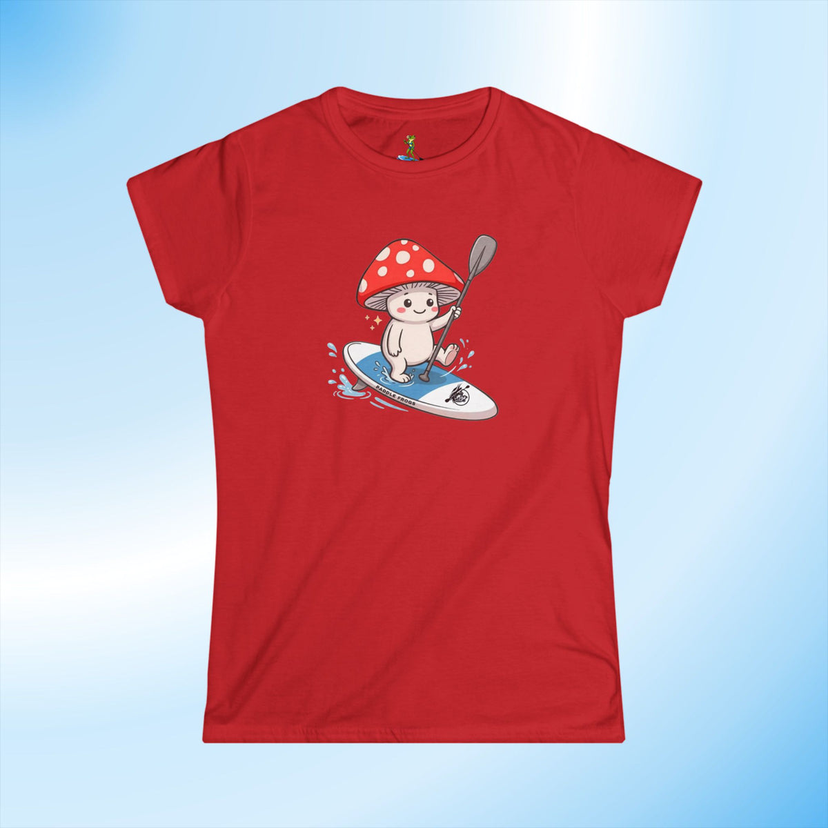 A female's red short-sleeve crewneck t-shirt featuring a cartoon graphic of a white mushroom with a red and white polka-dotted shroom cap and riding a blue SUP  with a paddle, set against a light blue gradient background. Made for woman who love paddleboarding by Paddle Frogs Outdoor Gear.