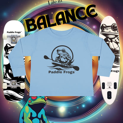 Blue t-shirt with 'Paddle Frogs' logo on a colorful background with skateboards and frogs.