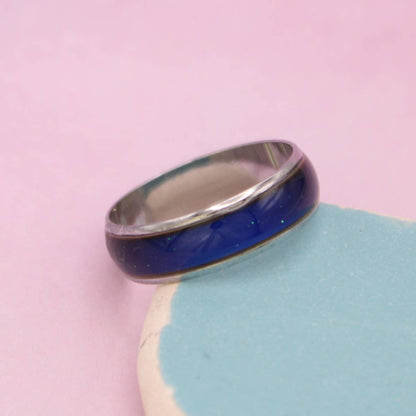 Silver mood ring with a blue band on a pink background