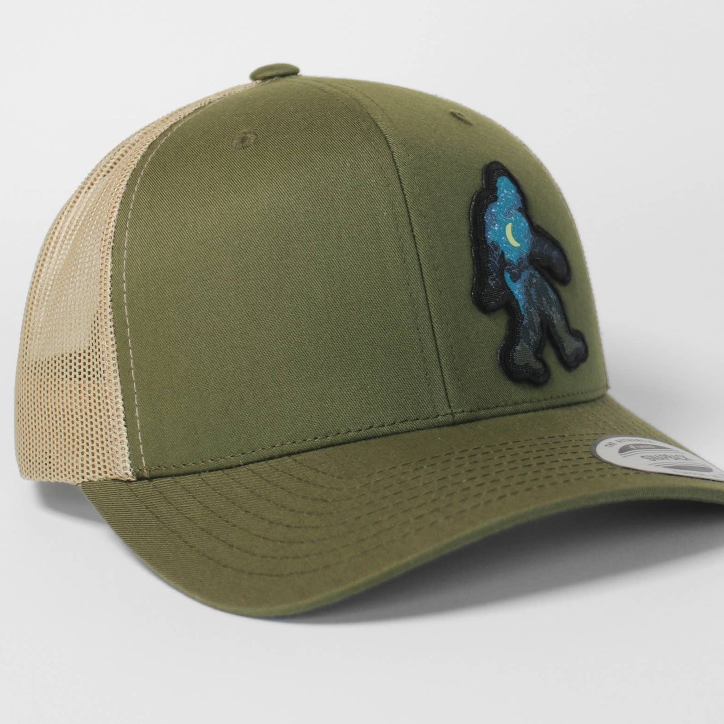 Green and beige cap with Bigfoot on a light gray background