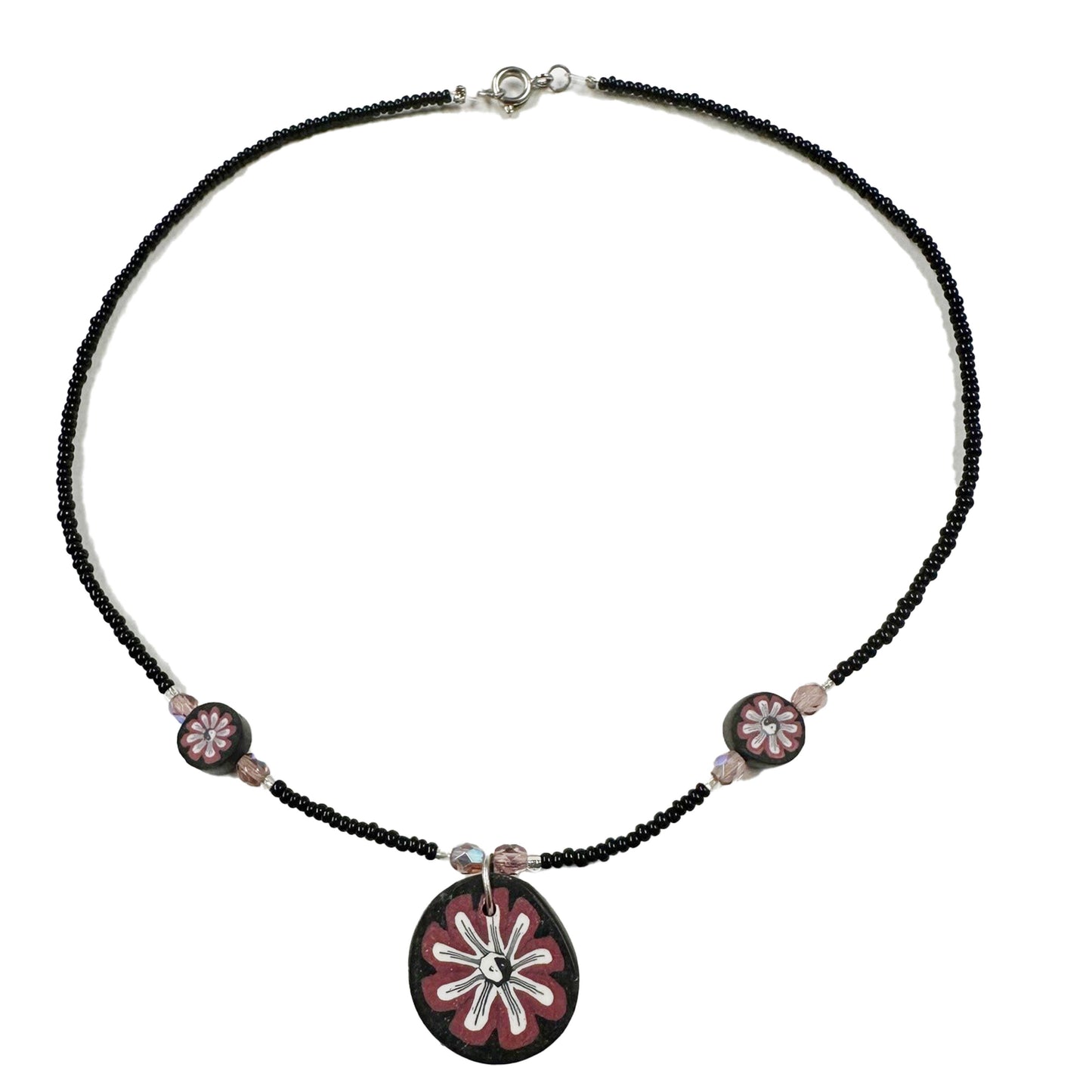 Necklace with black beads and pink floral pendant on a white background
