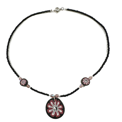 Necklace with black beads and pink floral pendant on a white background