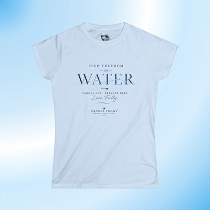 A light blue ladies short-sleeve t-shirt with a dark blue graphic print on the front that reads 'FIND FREEDOM ON WATER' and 'PADDLE FROGS'. The t-shirt is displayed against a light blue gradient background.