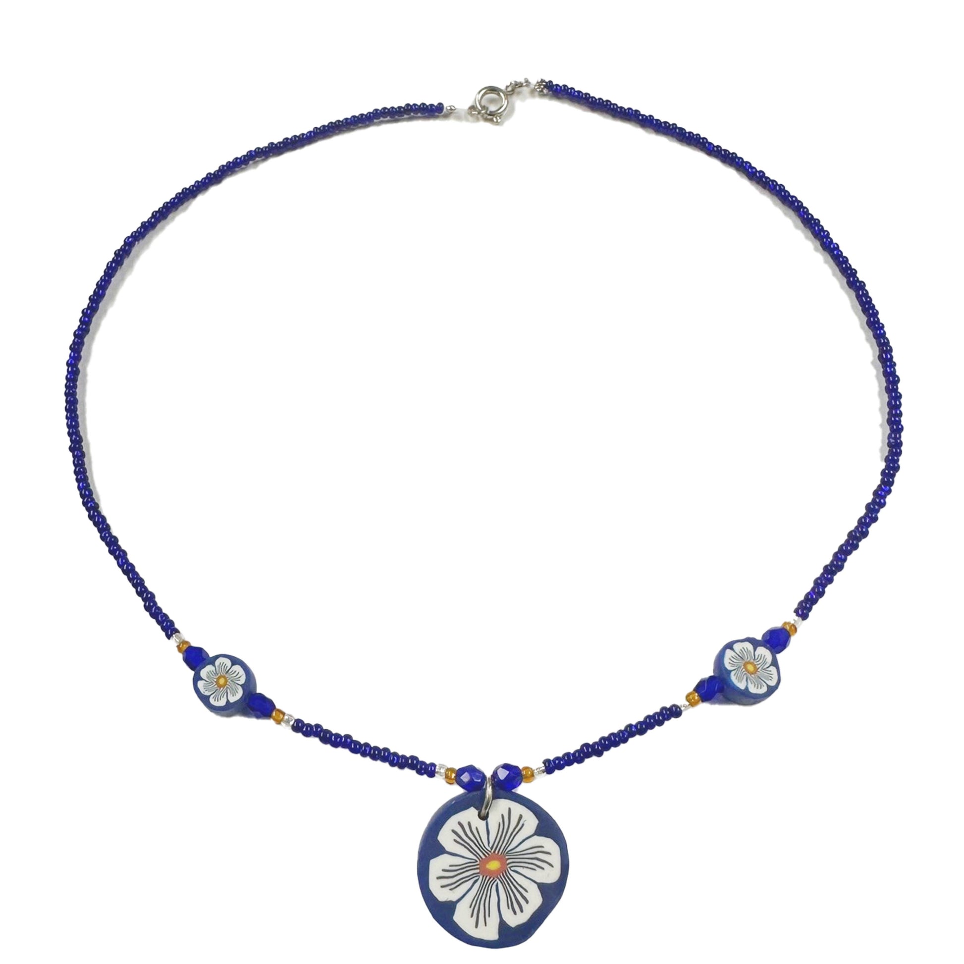 Necklace with blue beads and floral pendant on a white background
