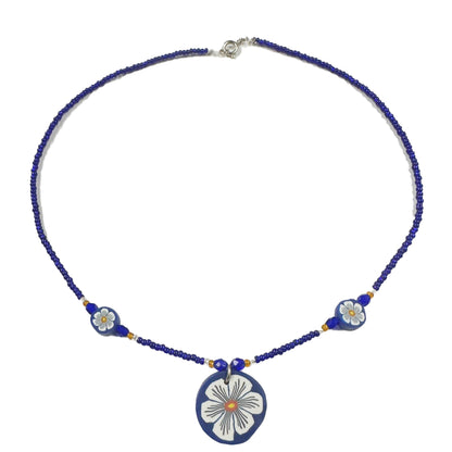 Necklace with blue beads and floral pendant on a white background