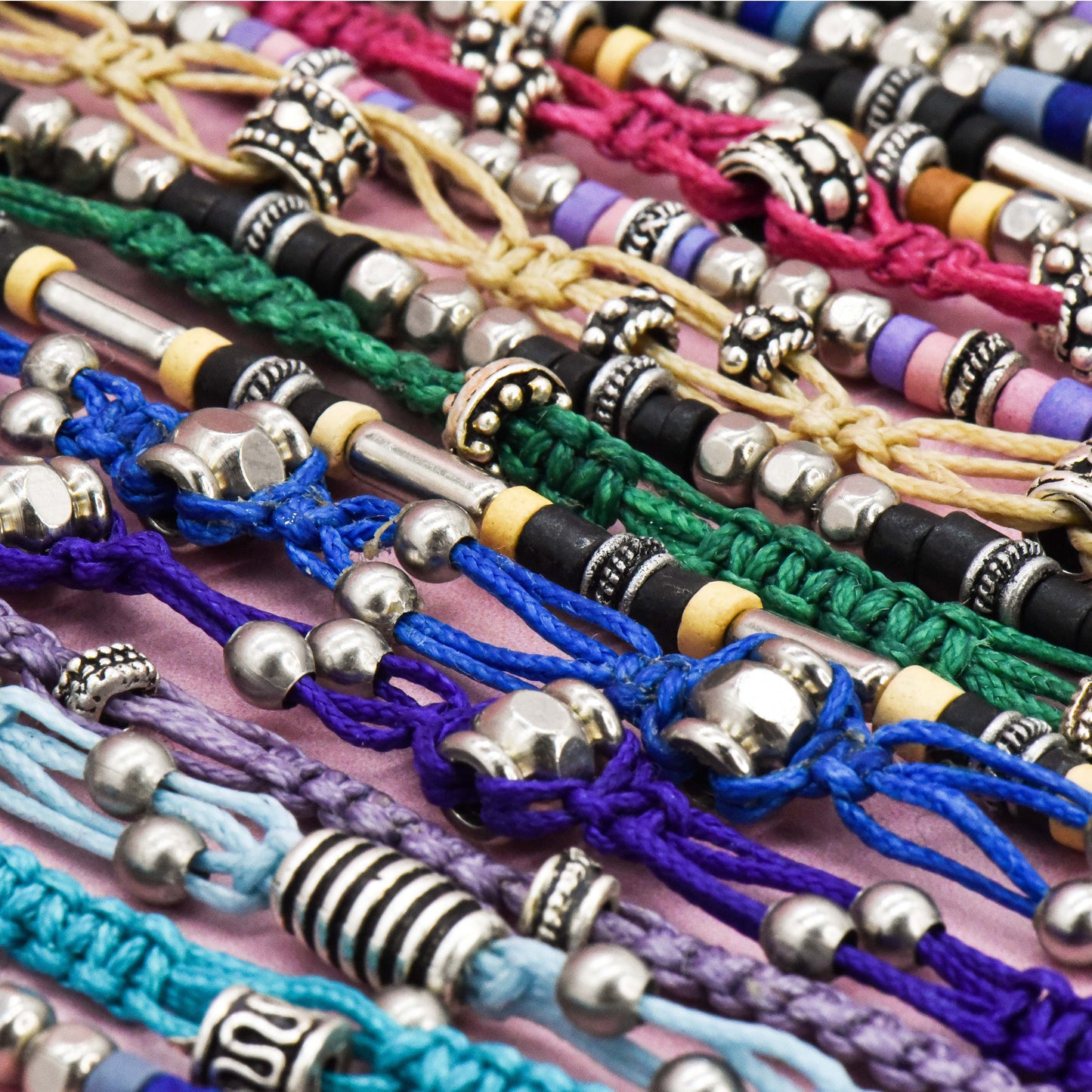 Collection of colorful bracelets with various bead designs on a pink surface