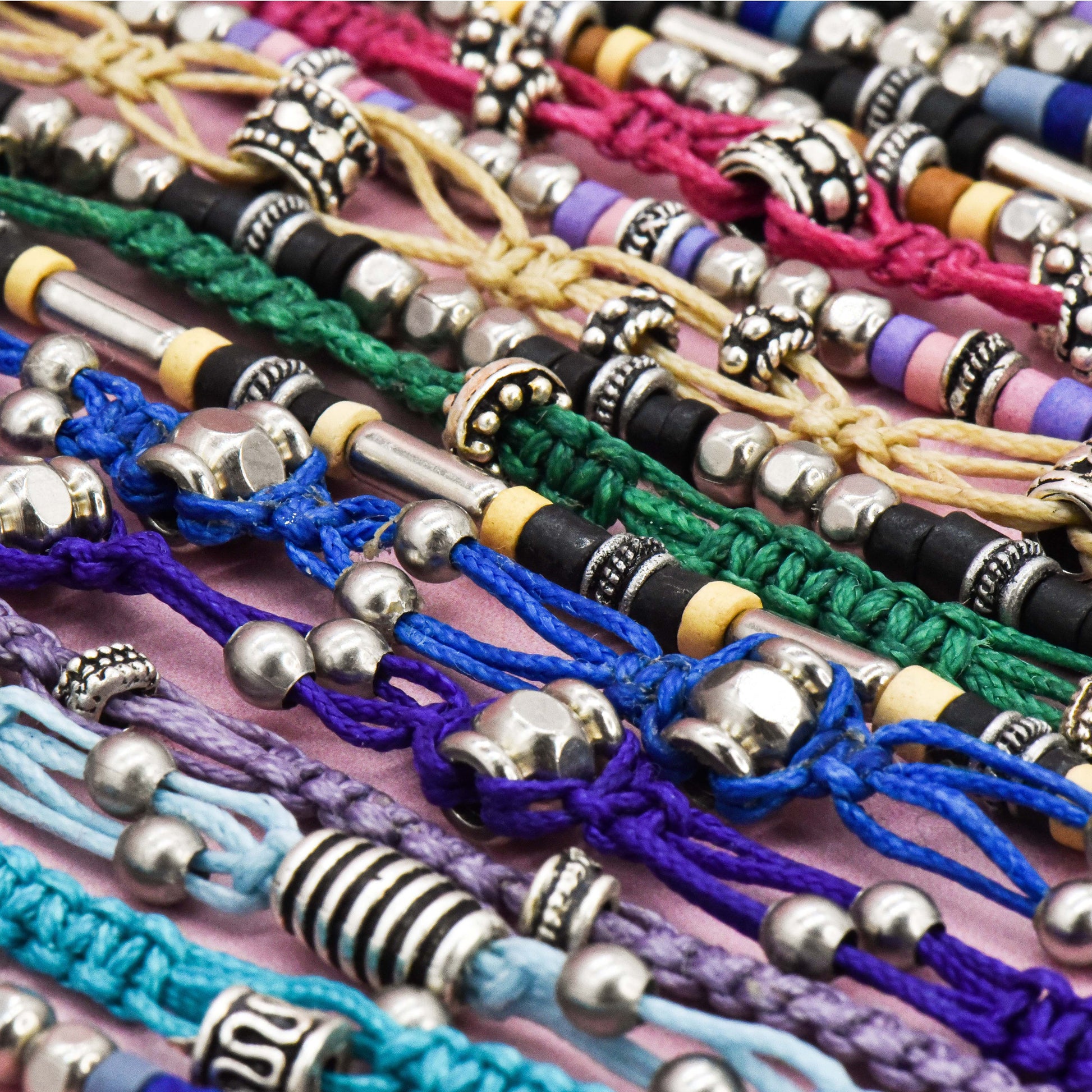 Collection of colorful bracelets with various bead designs on a pink surface