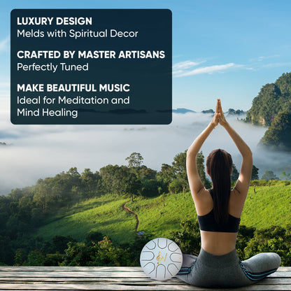 Person meditating with a tingsha drum on a wooden platform overlooking a scenic landscape.