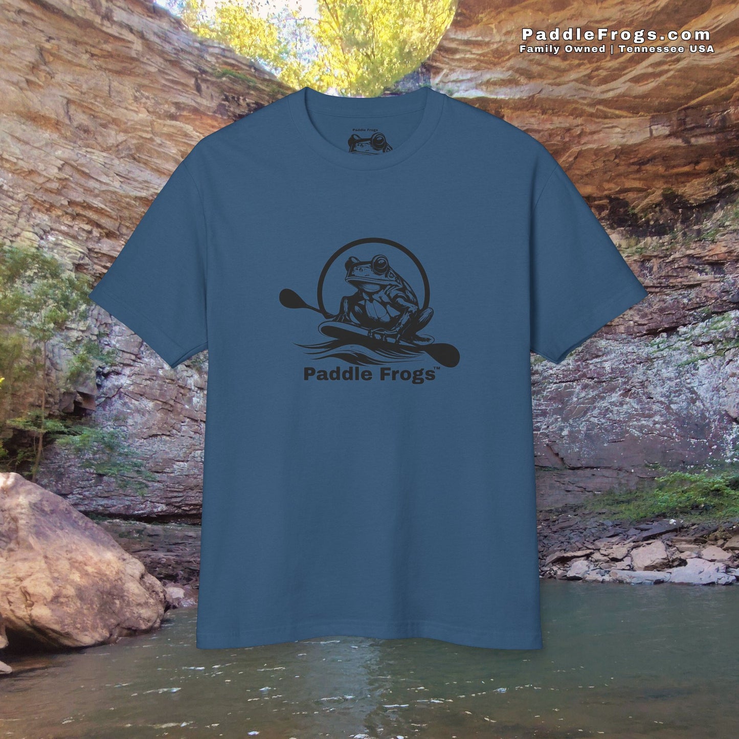 Blue t-shirt with 'Paddle Frogs' logo against a natural rock and water background