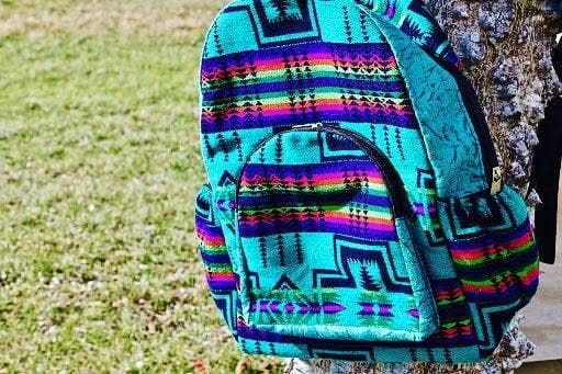 Colorful patterned backpack on a person standing outdoors with grass in the background