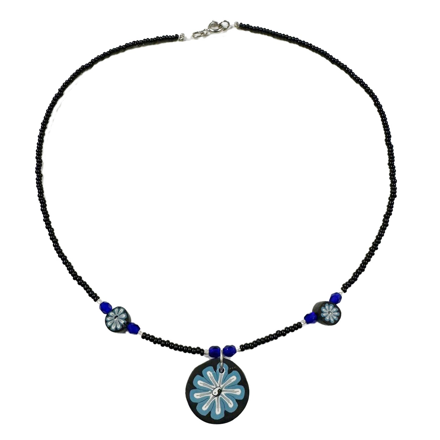 Necklace with black beads and a blue floral pendant on a white background