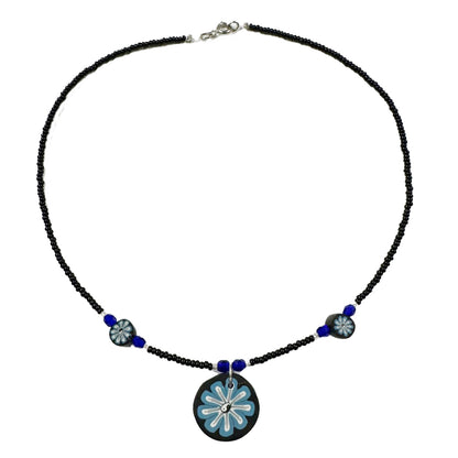 Necklace with black beads and a blue floral pendant on a white background