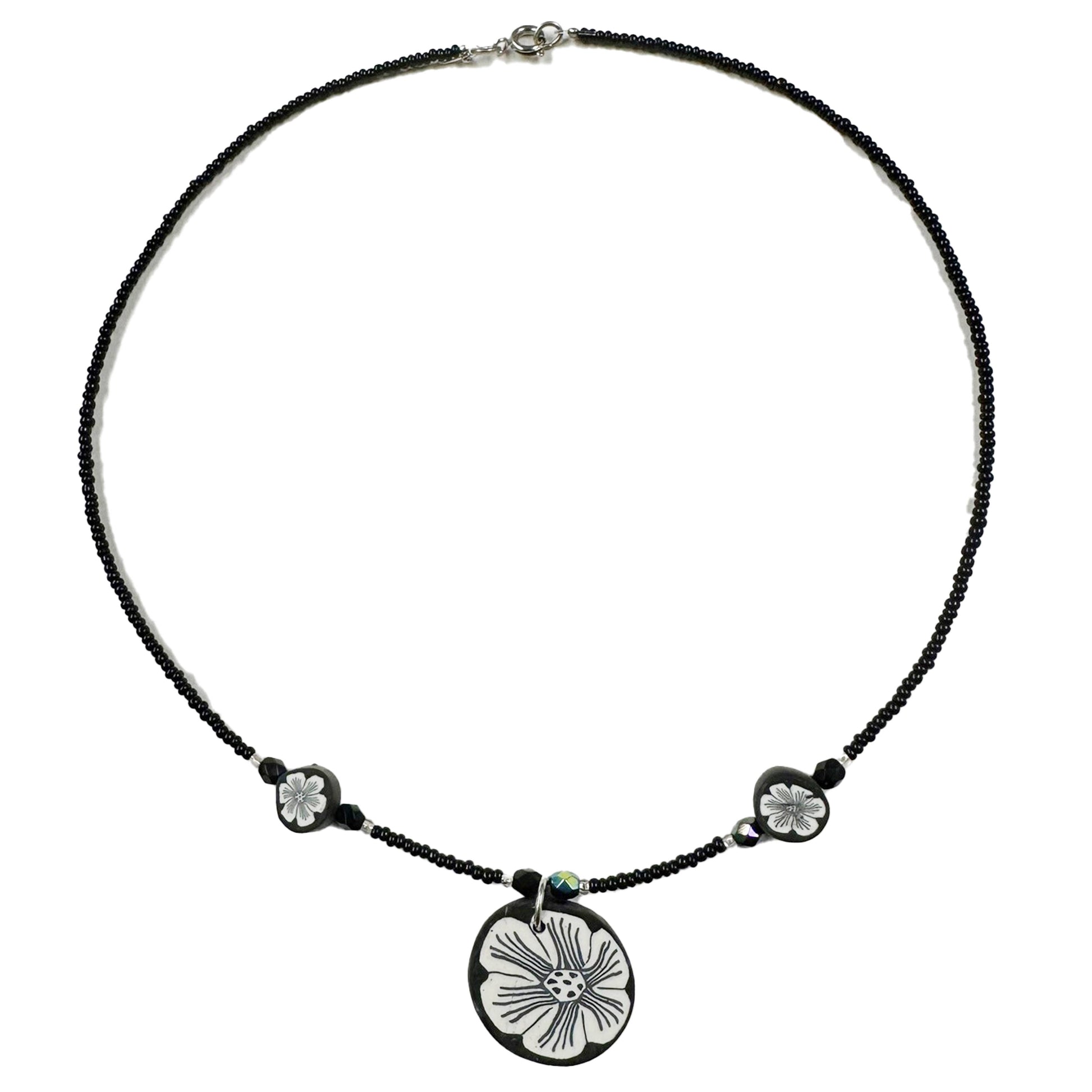 Necklace with a black cord and floral pendant on a white background
