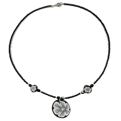 Necklace with a black cord and floral pendant on a white background