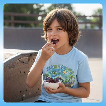 9 year old boy wearing Skate & Paddle | Volcano | Paddle Frogs™ Kids | Child eating from a bowl of fruit at a skate park.