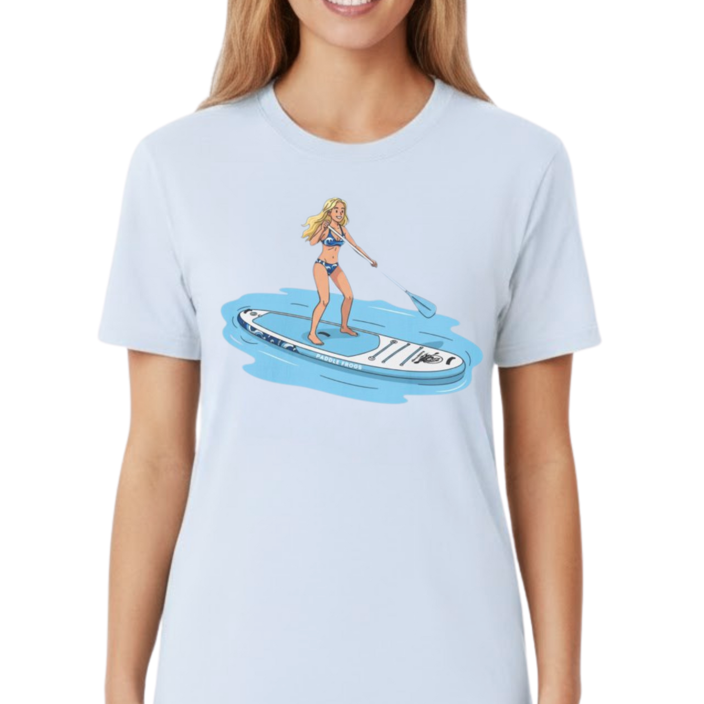 Light blue t-shirt with a graphic of a woman on a Divine Escape paddleboard by Paddle Frogs Outdoor Gear worn by a lady on a transparent background