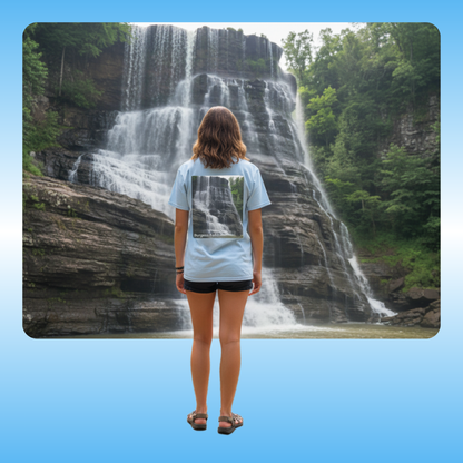  Burgess Falls, T-Shirt | Paddle Frogs Outdoor Gear | Tee | Person standing in front of a waterfall wearing a light blue t-shirt with a graphic design.