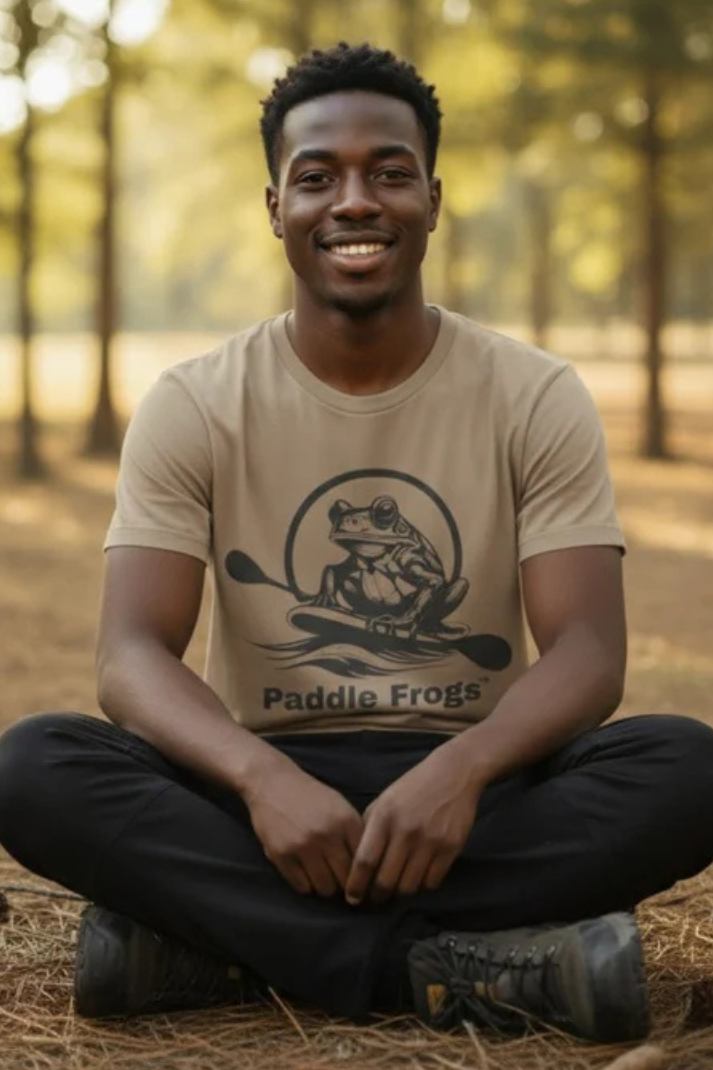 Man sitting crisscross applesauce wearing the faded tan Earthy Tee by Paddle Frogs Outdoor Gear in nature