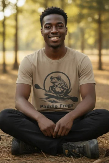 Man sitting crisscross applesauce wearing the faded tan Earthy Tee by Paddle Frogs Outdoor Gear in nature