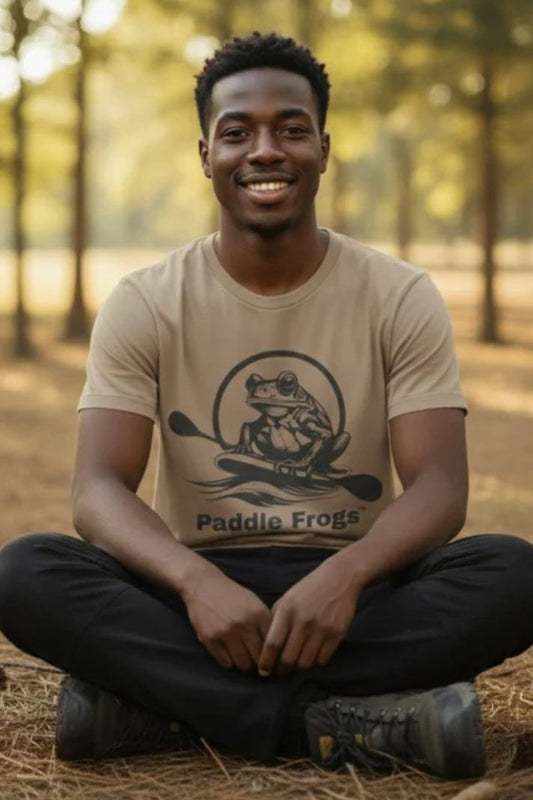 Man sitting crisscross applesauce wearing the faded tan Earthy Tee by Paddle Frogs Outdoor Gear in nature