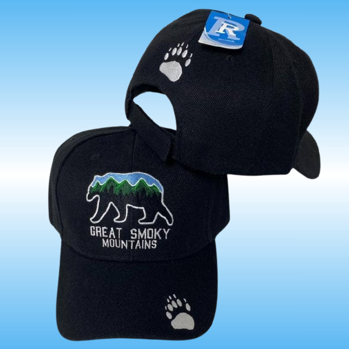 Ablack baseball caps shown on a blue gradient background. The front cap features an embroidered bear with green and blue mountain details and the text 'GREAT SMOKY MOUNTAINS,' plus a white paw print near the brim and above the adjustable backside.