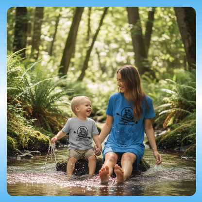 Grey toddler Paddle Frogs Tee and Ladies blue Paddle Frogs t-shirt dress Woman and child holding hands and wading through a stream in a forest
