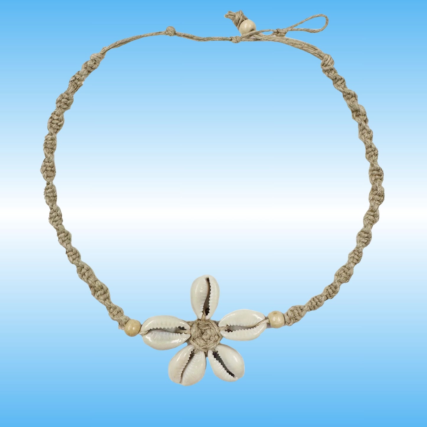 A handmade braided hemp necklace with a central flower charm made from five cowrie shells, set against a blue gradient background.