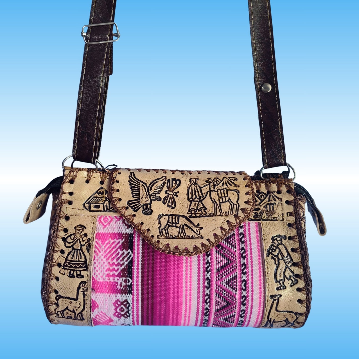 A handmade crossbody bag with a tan woven body featuring black embroidered motifs, a vibrant pink and purple striped textile panel, and dark brown leather straps.