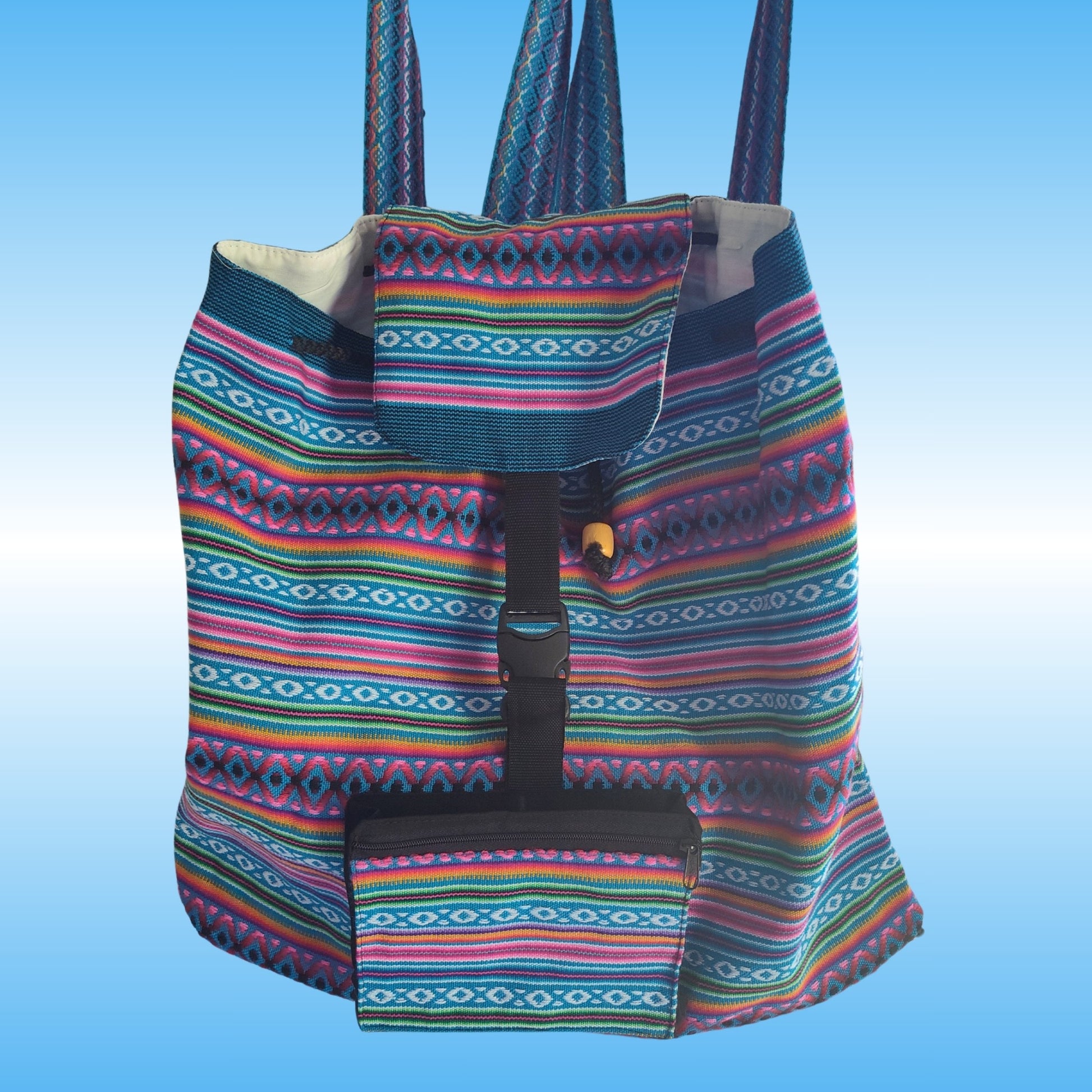 A colorful woven Peruvian backpack with a geometric multicolor pattern, featuring a front pocket and a black buckle strap closure, set against a light blue gradient background.