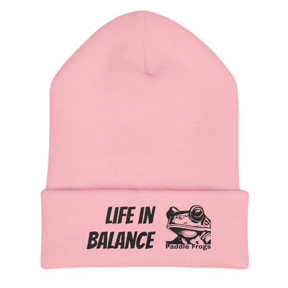Pink beanie with 'Life in Balance' and 'Paddle Frogs' text on a white background