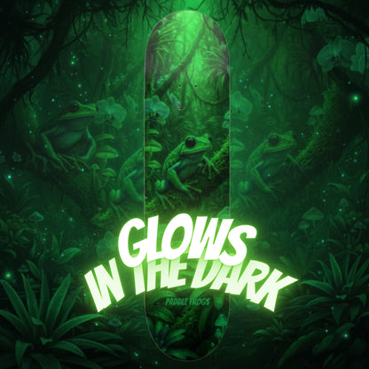 Skateboard with frog design and 'glows in the dark' text against a forest background
