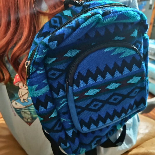 Blue patterned backpack held by a person with red hair.