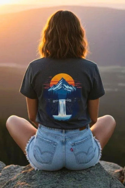 A lady sitting crisscross applesauce wearing the Mountain Sunrise | Pop Art Waterfall T-Shirt by Paddle Frogs outdoor gear