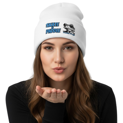 Woman wearing a white beanie with a logo and text, blowing a kiss.