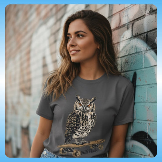 Woman wearing a gray t-shirt with an owl graphic against a graffiti-covered wall - Owl Skate & Paddle Tee - Paddle Frogs™ Outdoor Gear pro skate & paddle board shop - photography with model